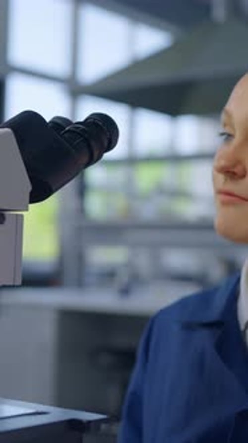 Girl Looks Through Microscope in Bright Lab