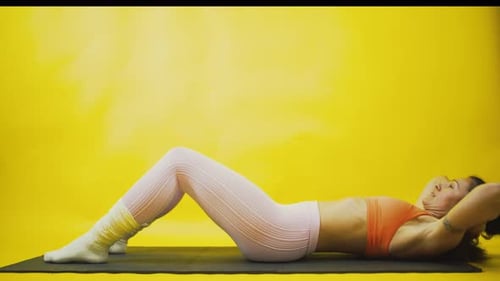 Femme athlétique faisant des crunches sur fond jaune