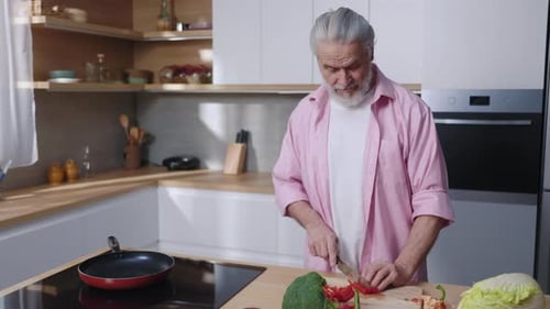 Senior Man Prepares Vegetables in Bright Kitchen