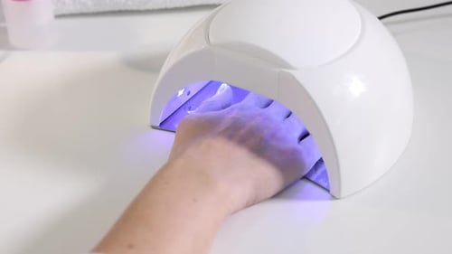 Woman Curing Gel Nail Polish with UV Light