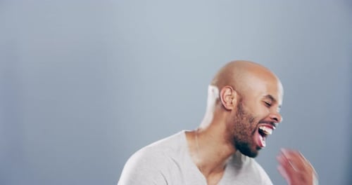 4k video footage of a young man laughing against a grey studio background