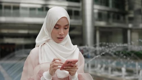 Woman Smiles While Using Mobile Phone in City