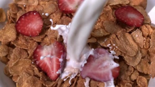 Milk pouring onto flakes and strawberries cereal