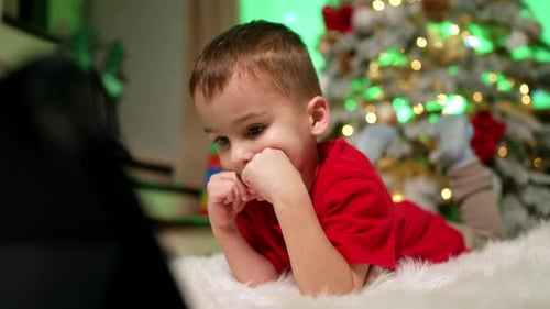 Child Watching Digital Tablet by Christmas Tree
