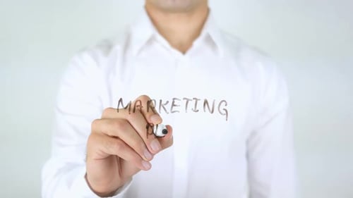 Writing 'Marketing Plan' with Marker on Glass