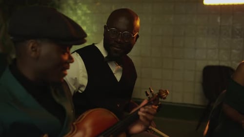 People playing stringed instruments indoors at night