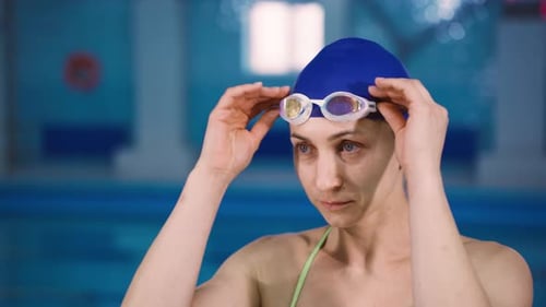 Woman Adjusting Goggles in Blue Swimming Pool
