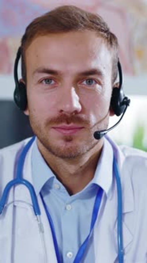 Portrait Man Doctor with Headphones in the Office Having Online Consulting Look at Camera Smiling