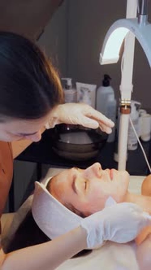 Woman Receiving Facial Treatment from Cosmetologist in Clinic