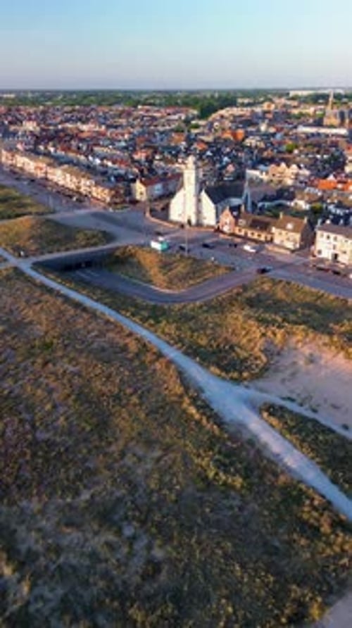 Aerial view of a coastal town with a white church beach dunes and walking paths The mix of buildings