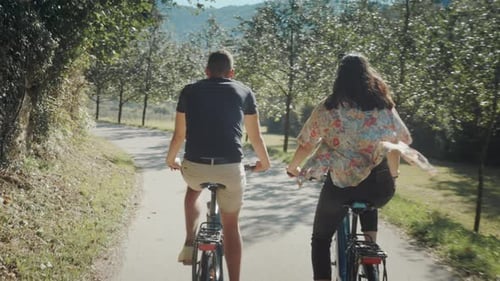 Couple Biking on Scenic Path Through Green Landscape