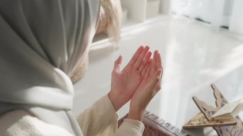 Asia muslim woman hand pray doa communicate to allah wear prayer clothes green mukena cover hijab.