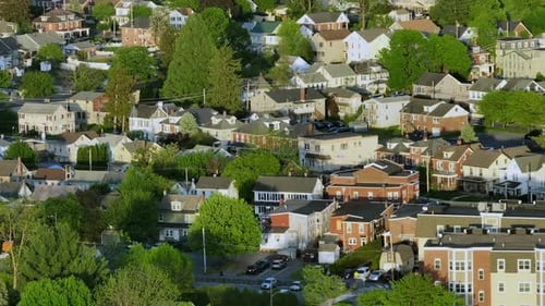Row of houses in american neighborhood during golden peaceful sunset time. Aerial wide shot. Green t