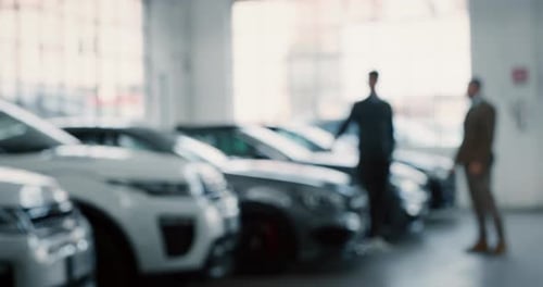 Men in Jackets Exchange Handshake in Car Showroom