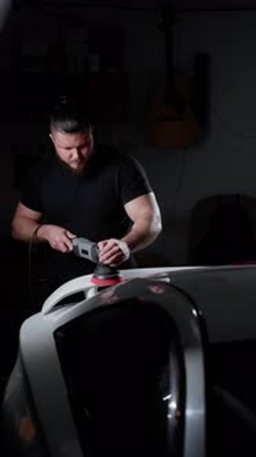 A Man Polishes a Car in a Garage