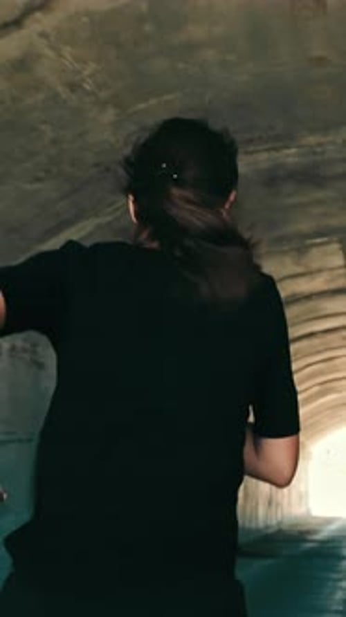 Woman Running in a Dark Tunnel to Meet the Light Silhouette of a Woman From Behind Running to the