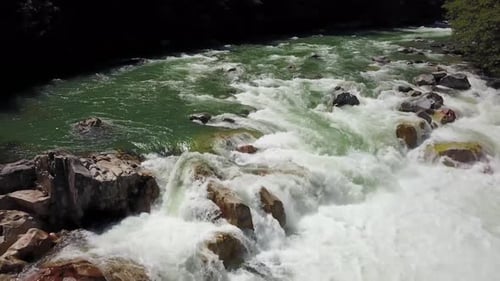 River Current Flowing in the Valley Around the Smooth Rocks During a Bright Sunny Spring Day
