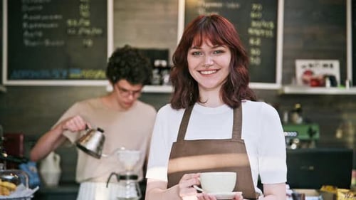 Portrait of Young Female Waitress in Front of Counter in Coffee Shop
