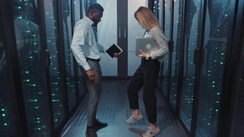 Data Center Technicians Inspecting Servers Using Tablet, Laptop