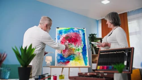 Elderly Couple Creating Abstract Painting Together Indoors