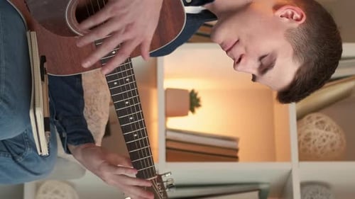 Young Adult Playing Acoustic Guitar Indoors