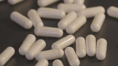Pills in Capsules Scattered on Gray Surface