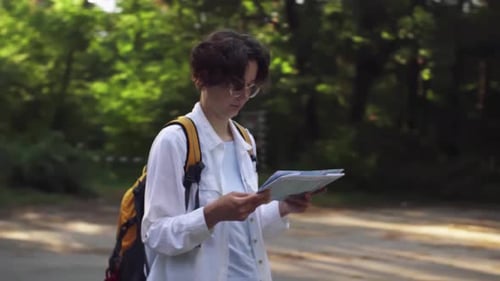 Young Adult Navigating Forest with Map and Backpack