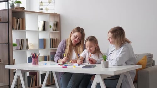 Women and Girl Drawing Together at White Table