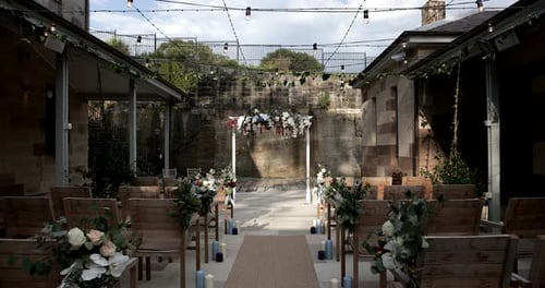 Rustic floral wedding arch at the end of aisle& rows of wooden chairs