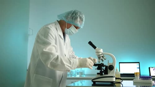 Focused Scientist Works With Microscope in Modern Lab