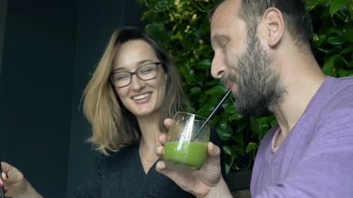 Happy, Young Couple Talking and Drinking Beverages Sitting on Sofa in Cafe Adult