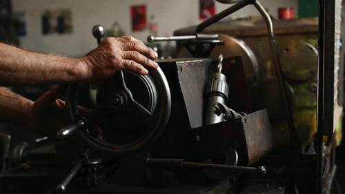 Close-up of worker's hands operating industrial machinery in workshop.
