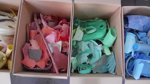 Colorful Plastic Waste Sorted by Color in Cardboard