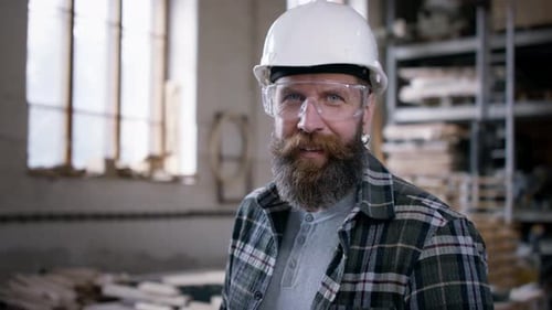 Carpenter in workshop stares at camera in his woodworking small business