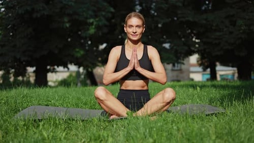 Pretty Lady Peacefully Meditating with Closed Eyes While Sitting on Yoga Mat