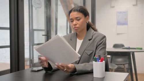 Woman Reviews Business Documents in Modern Office Setting