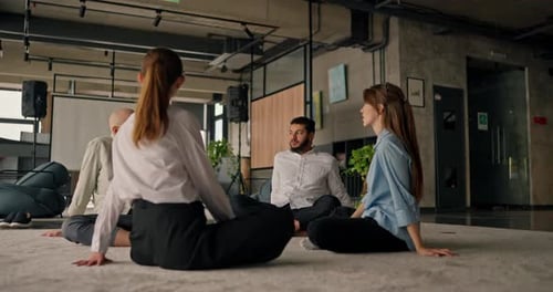 Group of Office Workers Sits in a Circle Engaging in Casual Conversation and Team Bonding During a