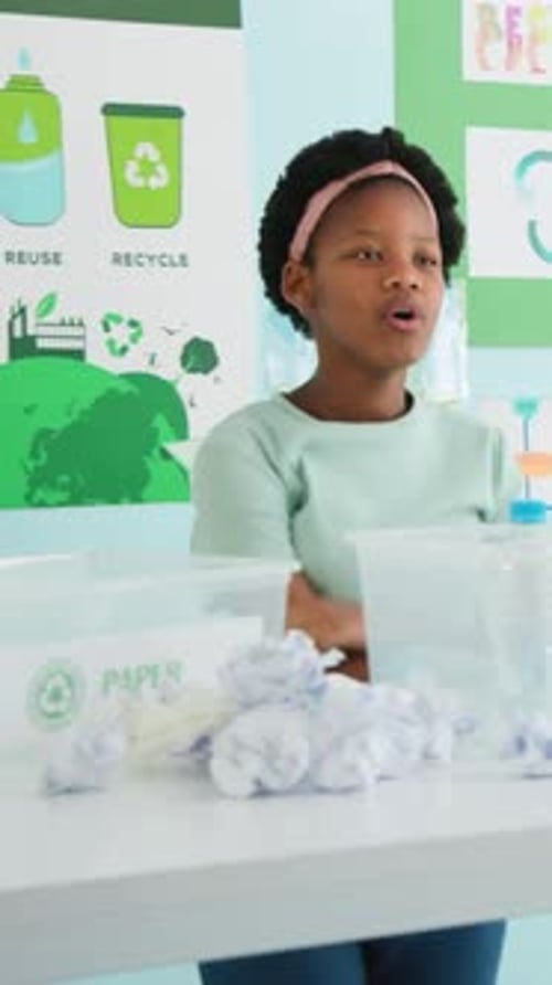 Vertical video: Pointing at posters at school, youth pink headband teaching sorting into PAPER bin