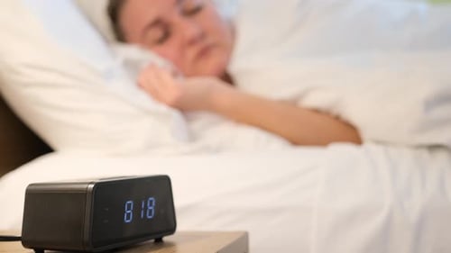 Woman Sleeping Peacefully with Alarm Clock Showing Morning Time