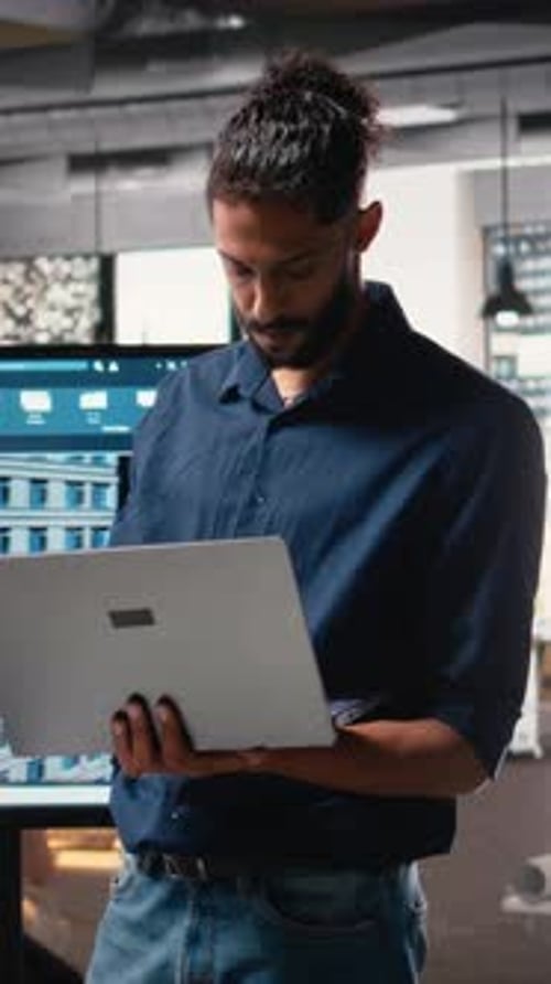 Man Standing Working in Modern Office With Laptop