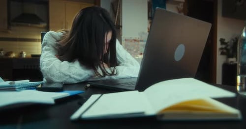 Tired Student Works on Laptop at Home