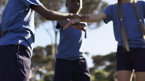 African American kids stacking hands, camera rising, raising arms, cheering on field in blue shirts