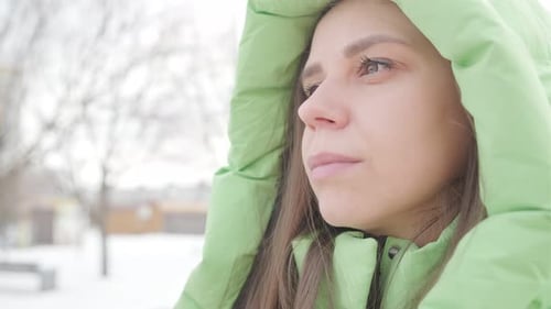 A Young Woman Reflects Thoughtfully While Enjoying a Snowy Winter Afternoon in a Quiet Park Setting