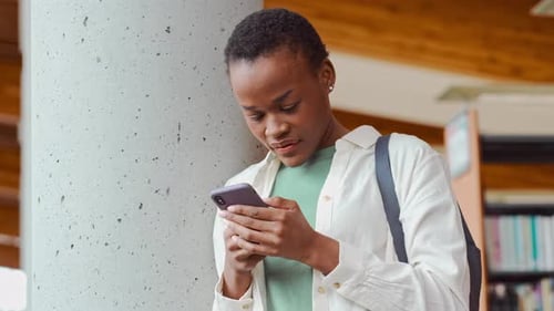 Young Woman Uses Phone in Modern Library