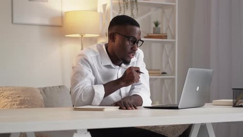 Man Video Conferencing at Desk with Laptop