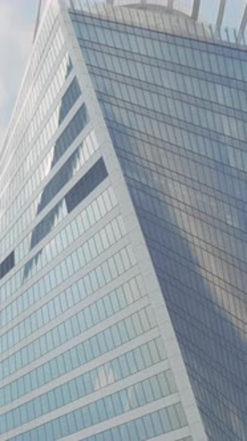 Bottom View of a Twisted Skyscraper on Blue Cloudy Sky Background Action Glass Facade Tall Buildings
