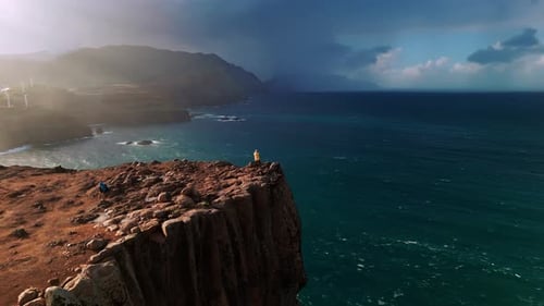 Woman Hiker Atop Rugged Coastal Cliffs Overlooking Sea