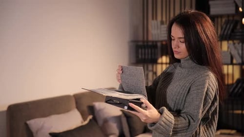 Woman Examining Fabric Samples in Warmly Lit Home
