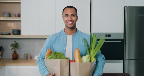 Young Adult Holding Groceries in Bright Kitchen