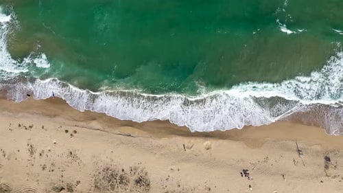 Aerial view of ocean waves washing a secluded sandy shoreline beach